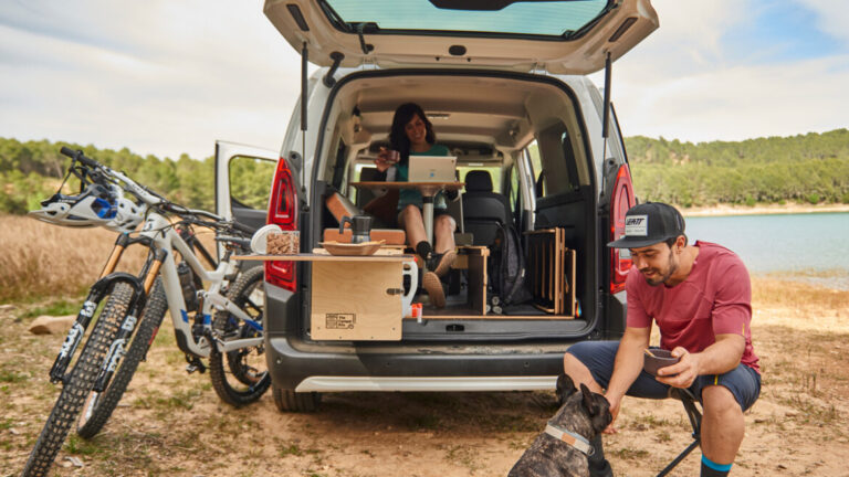 Dos personas y un perro, una sentada con un portátil en la mesa del Kit Nömad Flex