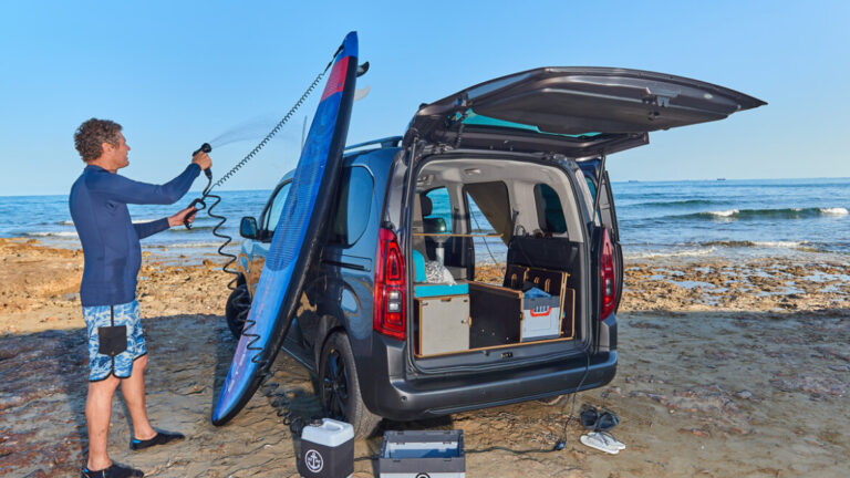 Una persona con tabla de surf al lado una furgoneta con el Kit Nömad Flex